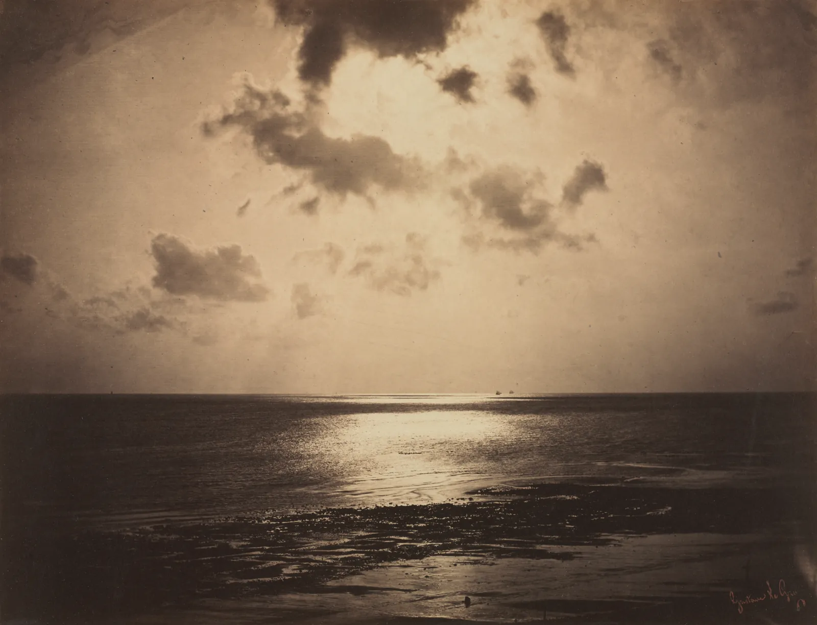 A sepia photograph of the sea with the sun behind clouds and a path of light on the water.